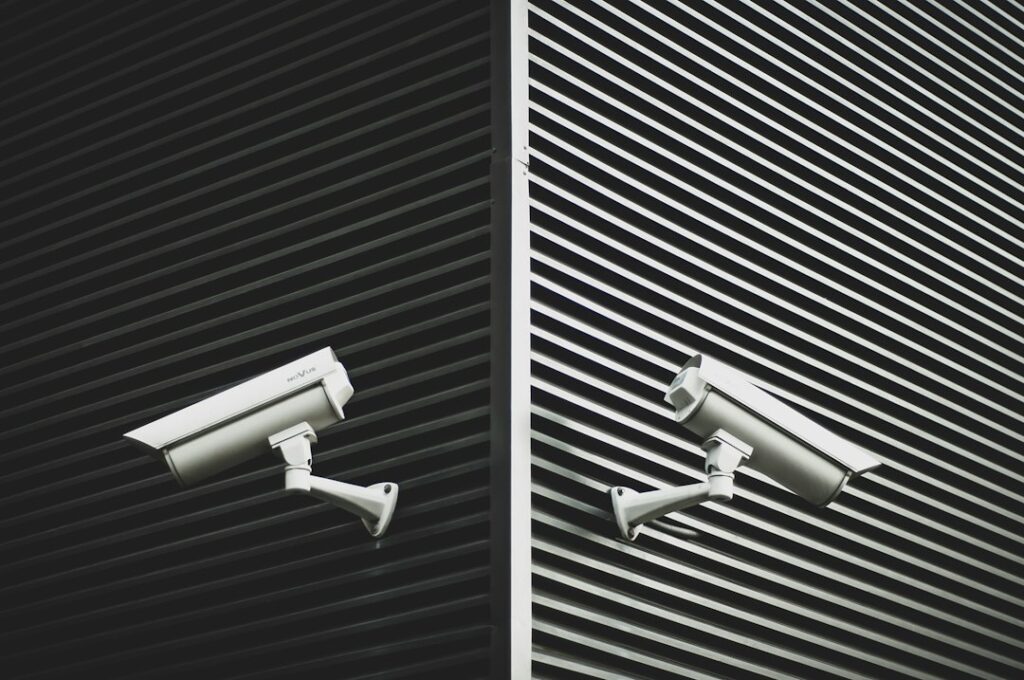 Homeowner reviews door sensors and a security camera feed on a tablet near a residential entryway.