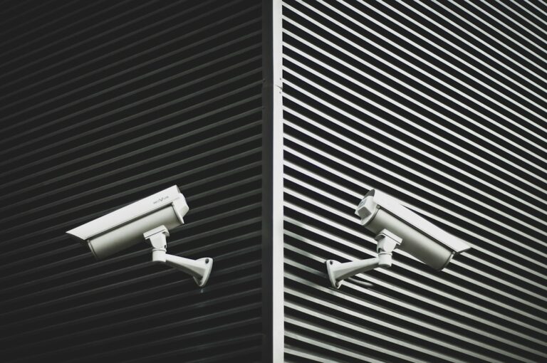 Homeowner reviews door sensors and a security camera feed on a tablet near a residential entryway.